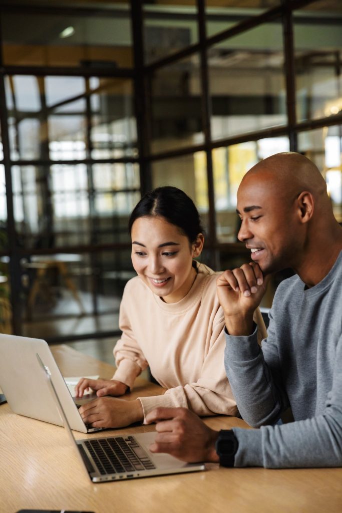 Why-ASD-2 man and women looking at laptop screens together smiling